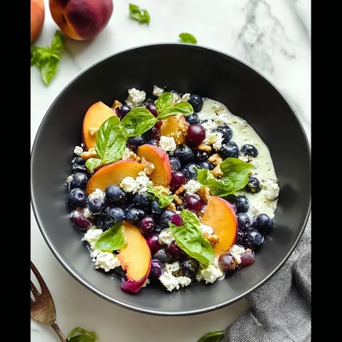 A bowl of fruit with blueberries, peaches, and feta cheese.