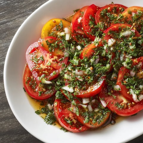 A bowl of sliced tomatoes with herbs.