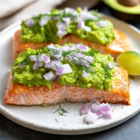 A plate of fish with avocado and lime.
