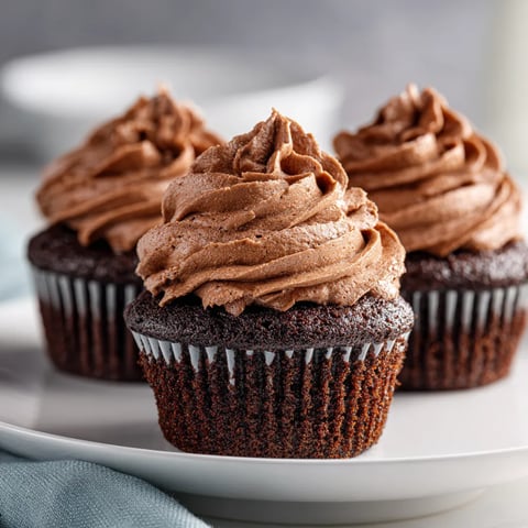 Three chocolate cupcakes with frosting.