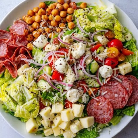 A plate of food with meat, cheese, lettuce, tomatoes, and beans.