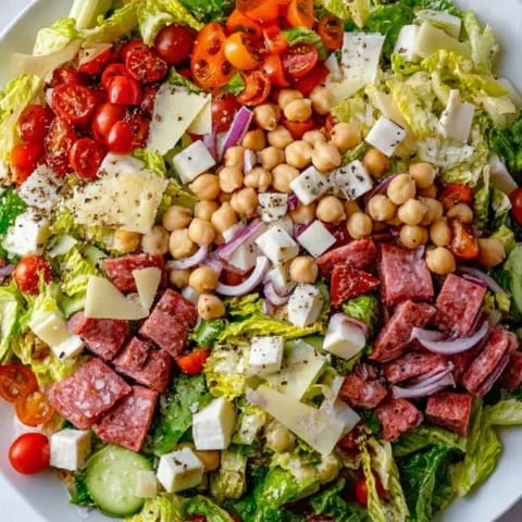 A plate of salad with tomatoes, lettuce, and chickpeas.